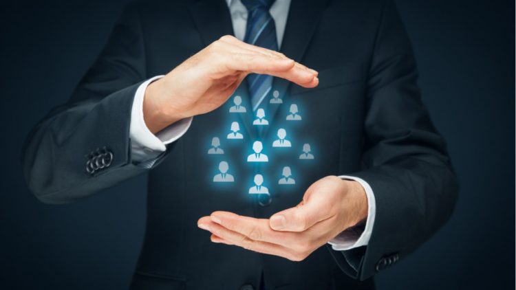Businessman in a suit holding virtual icons of people, symbolizing team management.