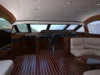 Elegant yacht cockpit and lounge area with leather seating, wooden flooring, and panoramic windows offering a view of the sea.