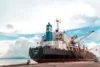 Close-up view of a ship's superstructure and cranes under a cloudy sky.