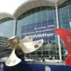 Entrance to the SMM fair with a large ship propeller on display, and a banner reading 'driving the maritime transition' on the glass facade.